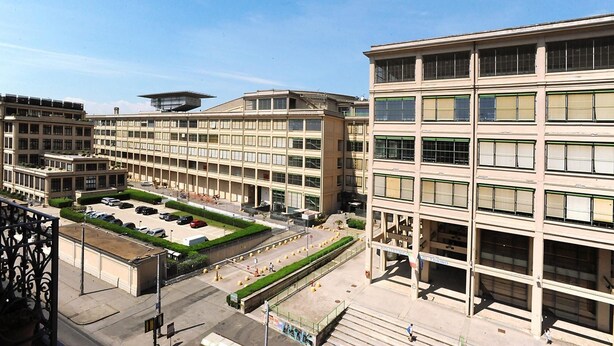 A multi-story building with a central courtyard, featuring a parking area and a pedestrian walkway.