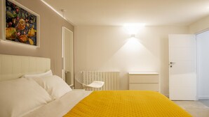 Un dormitorio con cama, una silla, un radiador y una puerta.