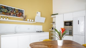Una cocina moderna con armarios blancos, una mesa de comedor de madera y un cuadro abstracto y colorido en la pared.