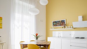Una cocina moderna con armarios blancos, estufa integrada y una ventana con cortinas de gasa.