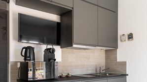 A modern kitchen with grey cabinets, a built-in microwave, and a coffee maker.