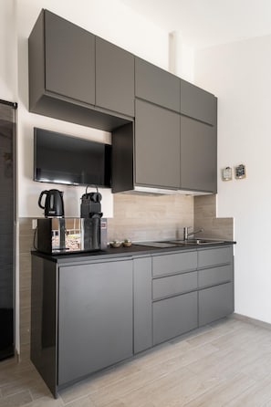 A modern kitchen with grey cabinets, a built-in microwave, and a coffee maker.