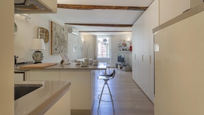 A kitchen with a central island, bar stools, and a view into the dining area. - Nel Cuore del Borgo di Camogli by Wonderful Italy (Camogli)