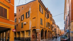 A narrow street with yellow buildings, a no entry sign, and parked bicycles. - Studio Malcontenti con Terrazzo by Wonderful Italy (Bologna)