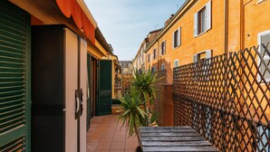 A narrow alleyway with a wooden bench, a potted plant, and a metal fence. - Studio Malcontenti con Terrazzo by Wonderful Italy (Bologna)