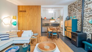 Ein modernes Wohnzimmer mit einer Couch, Couchtisch und einem Essbereich mit Stühlen und Tisch. Im Hintergrund ist eine Küche mit Herd und Schränken zu sehen.