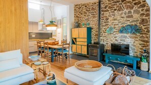 Ein modernes Wohnzimmer mit Steinwand, Kamin und Essbereich mit Holzmöbeln.