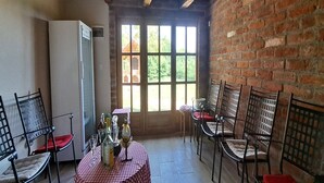 Ein Zimmer mit karierter Tischdecke, Stühlen, einem Kühlschrank und einem Fenster mit Blick auf Grünflächen.