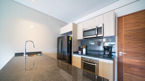 Une cuisine moderne dotée de plans de travail en granit, d’appareils électroménagers en acier inoxydable et de meubles en bois.