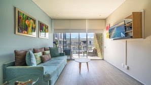 Un salon moderne avec un canapé, une table basse en verre et un téléviseur fixé au mur.