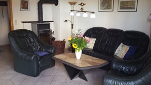 Ein Wohnzimmer mit zwei schwarzen Ledersofas, einem Couchtisch und einem Kamin.