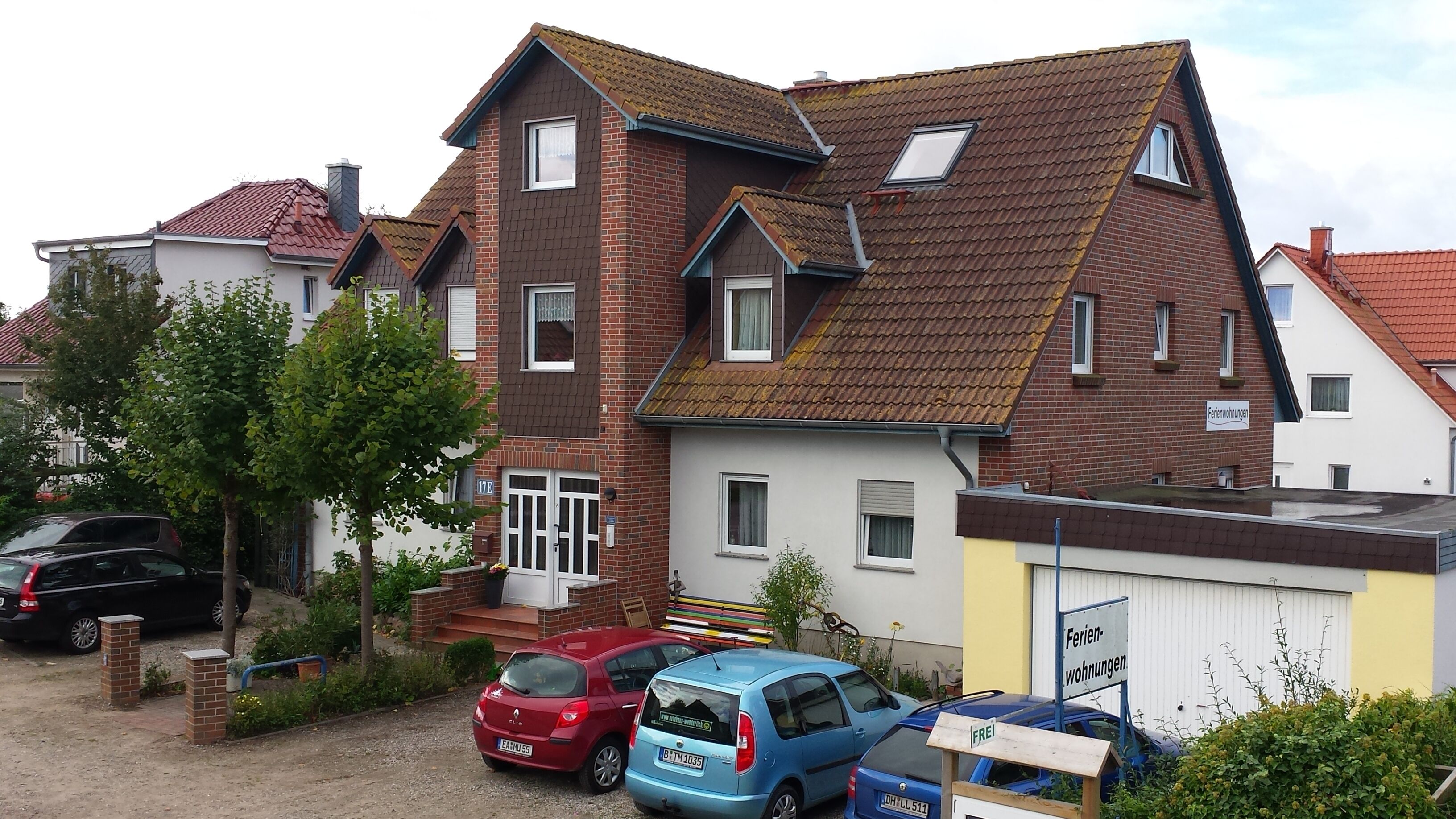 A two-story residential building with a sloped roof, a visible chimney, and a small window on the upper floor.