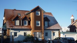 Ein zweistöckiges Haus mit Ziegeldach, Backsteinfassade und Schornstein. Ein Auto steht auf der Auffahrt.