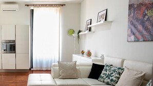 A modern living room with a sectional sofa, a glass coffee table, and a kitchen area in the background. - Agatea a due Passi dal Duomo by Wonderful Italy (Catania)