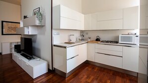 A modern kitchen with white cabinets, a microwave, a gas stove, and a built-in TV. - Agatea a due Passi dal Duomo by Wonderful Italy (Catania)