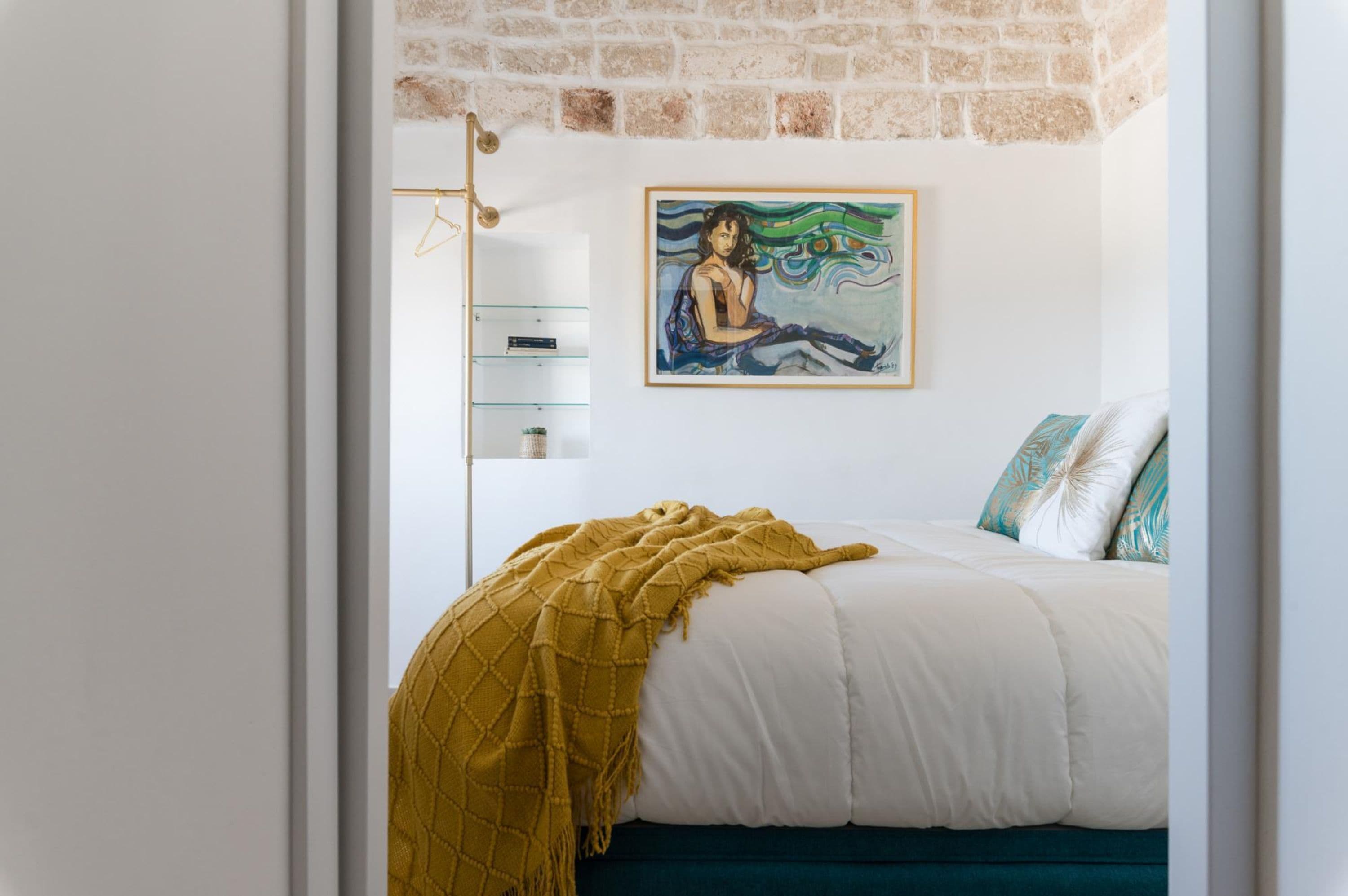 Ein Schlafzimmer mit einem Bett, einem Gemälde an der Wand und einer Ziegelwand über dem Bett.
