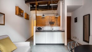 A compact kitchen with white cabinets, a microwave, and a sink. There is a wooden ceiling beam, a hanging light fixture, and a small wooden shelf on the wall. - San Michele Apts by Wonderful Italy - Aluminium (Bologna)