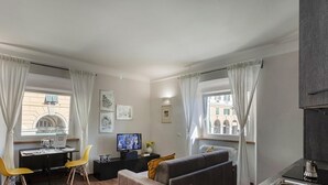 Una sala de estar moderna con comedor, televisor y sofá.