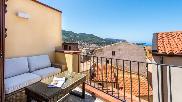 Un balcon avec un canapé et une table, offrant une vue sur le paysage urbain et la mer.