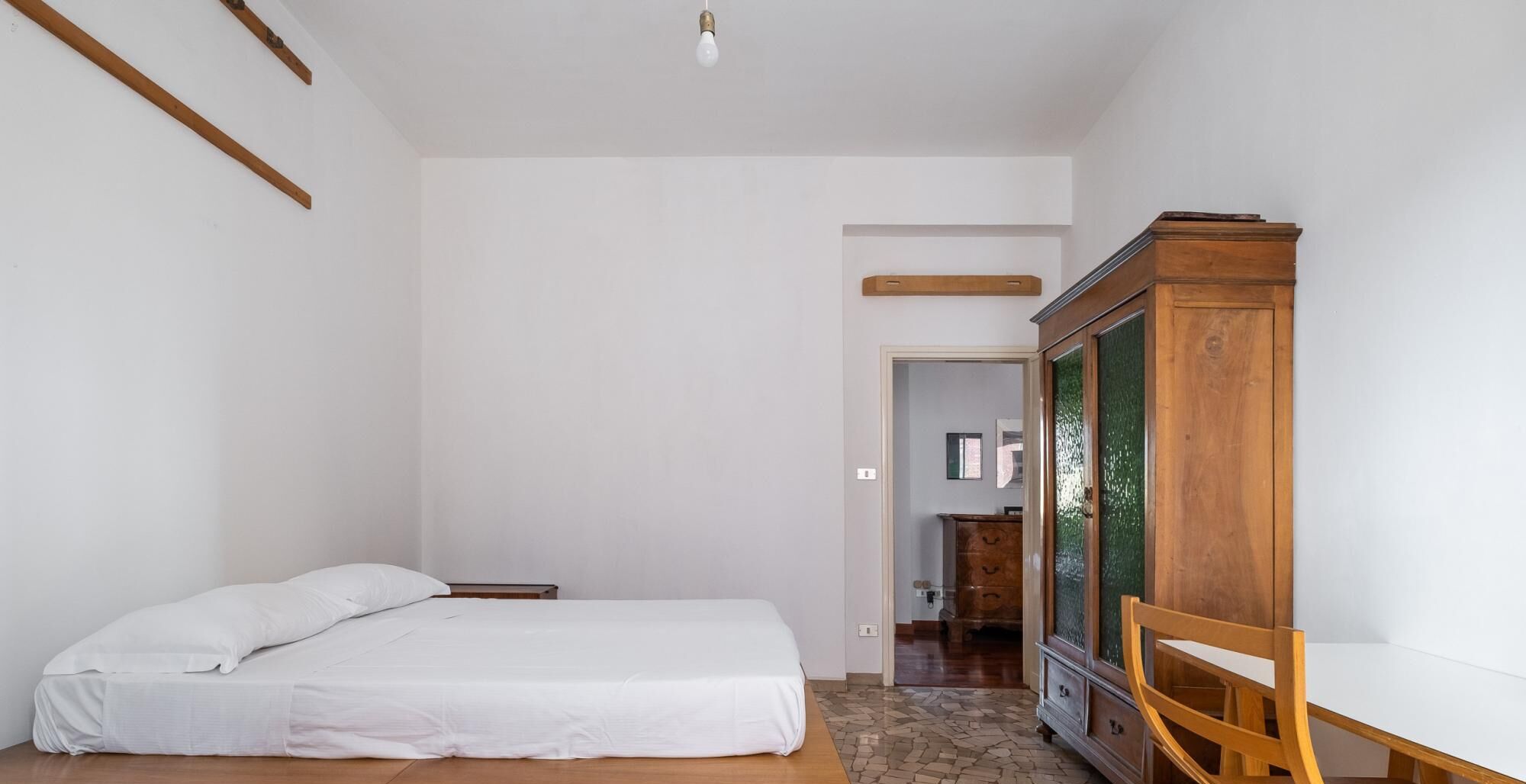 Ein Schlafzimmer mit einem Bett, einem Holzschrank und einem Schreibtisch.