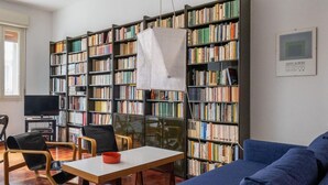 A library with bookshelves, a table, chairs, and a blue sofa.