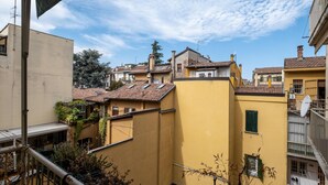 A residential area with yellow buildings, a balcony with a metal railing, and a clear blue sky.