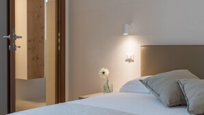 A bedroom with a bed, a nightstand, a wall-mounted light, and a door. - Charming Villa With Pool by Wonderful Italy (Ostuni)