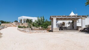 A modern villa with a gravel driveway, stone walls, and a pergola with outdoor seating. - Charming Villa With Pool by Wonderful Italy (Ostuni)