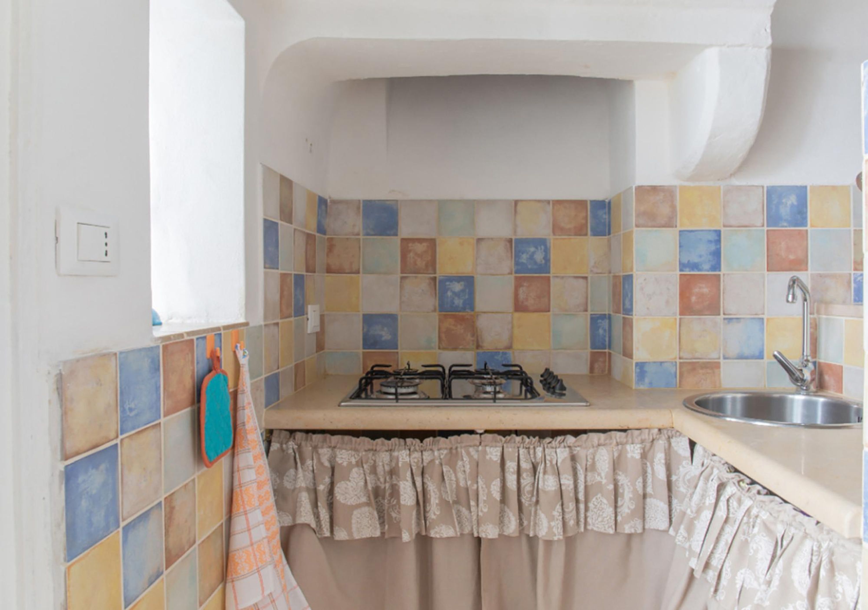 A kitchen with a gas stove, a sink, and a tiled backsplash.