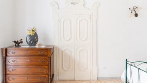 Een kamer met een houten dressoir, een witte deur en een bed met een metalen frame.