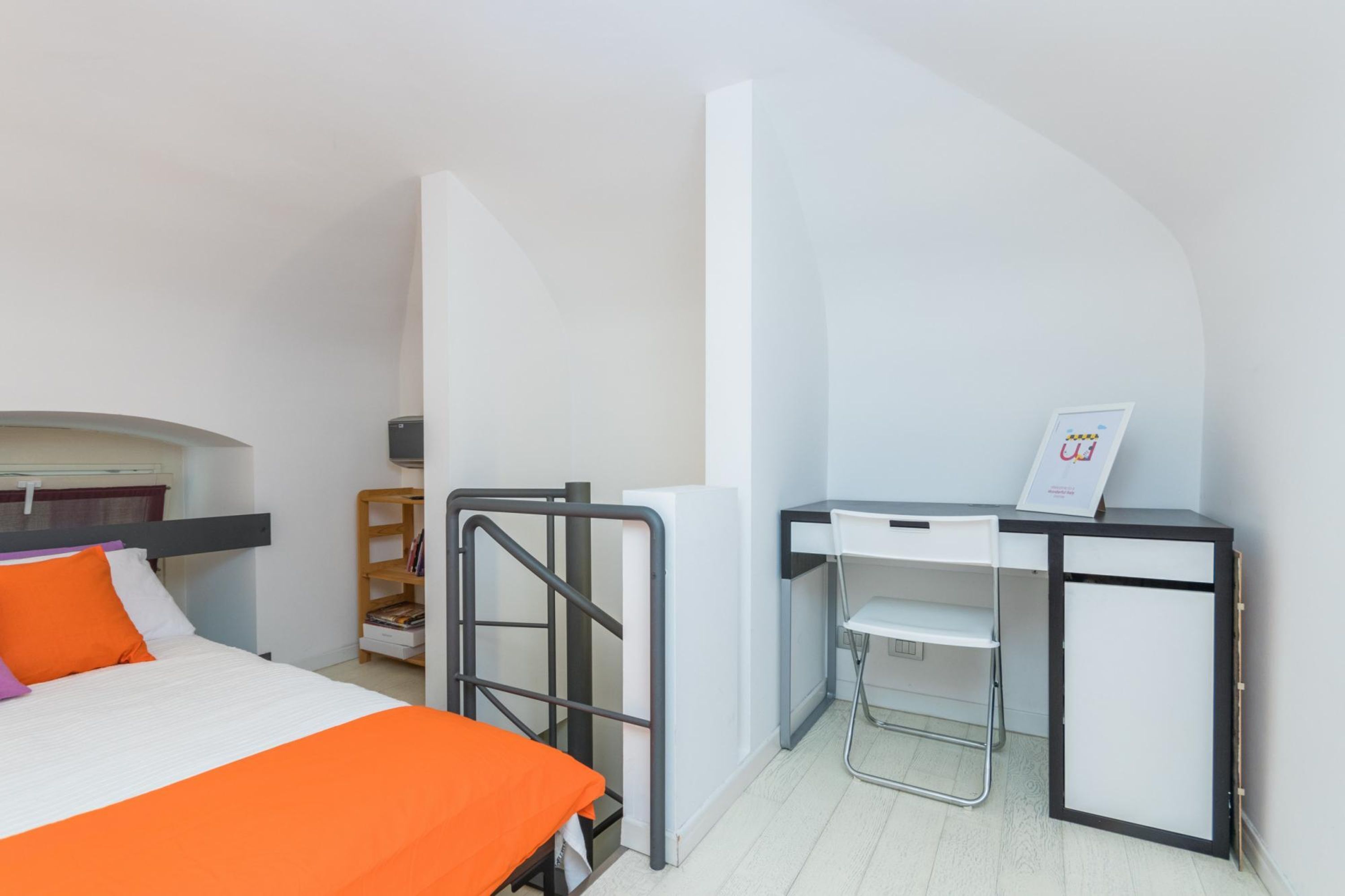 Ein kleines Hotelzimmer mit einem Bett, einem Schreibtisch und einem Stuhl.