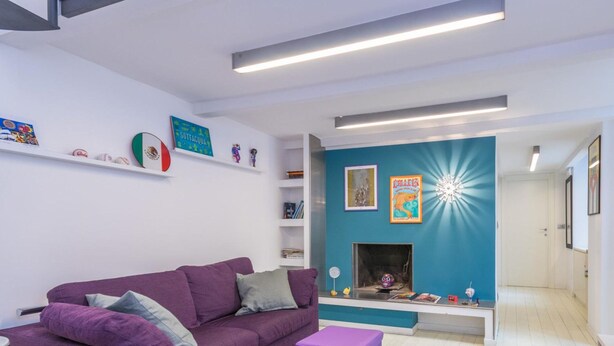 Ein modernes Wohnzimmer mit einem violetten Sofa, einem Kamin und einem Fernseher.