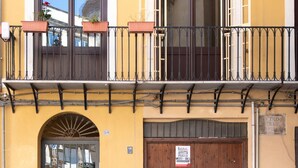 A yellow building with a wooden door, a balcony with metal railings, and a window with a reflection. - Casa Meli in Piazza S Domenico by Wonderful Italy (Palermo)