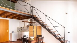 A modern kitchen with a wooden ceiling, a dining area with a table and chairs, and a staircase with metal railings. - Casa Meli in Piazza S Domenico by Wonderful Italy (Palermo)