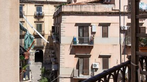 A narrow street with buildings on either side, balconies with laundry hanging, and a clear blue sky. - Casa Meli in Piazza S Domenico by Wonderful Italy (Palermo)