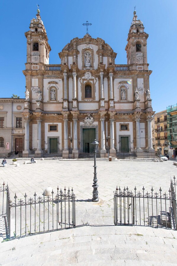 A historic building with two towers, a central entrance, and a surrounding plaza.