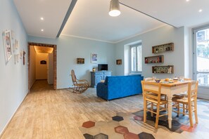 Un salon moderne avec un canapé bleu, une table à manger en bois et un tapis à motifs hexagonaux.