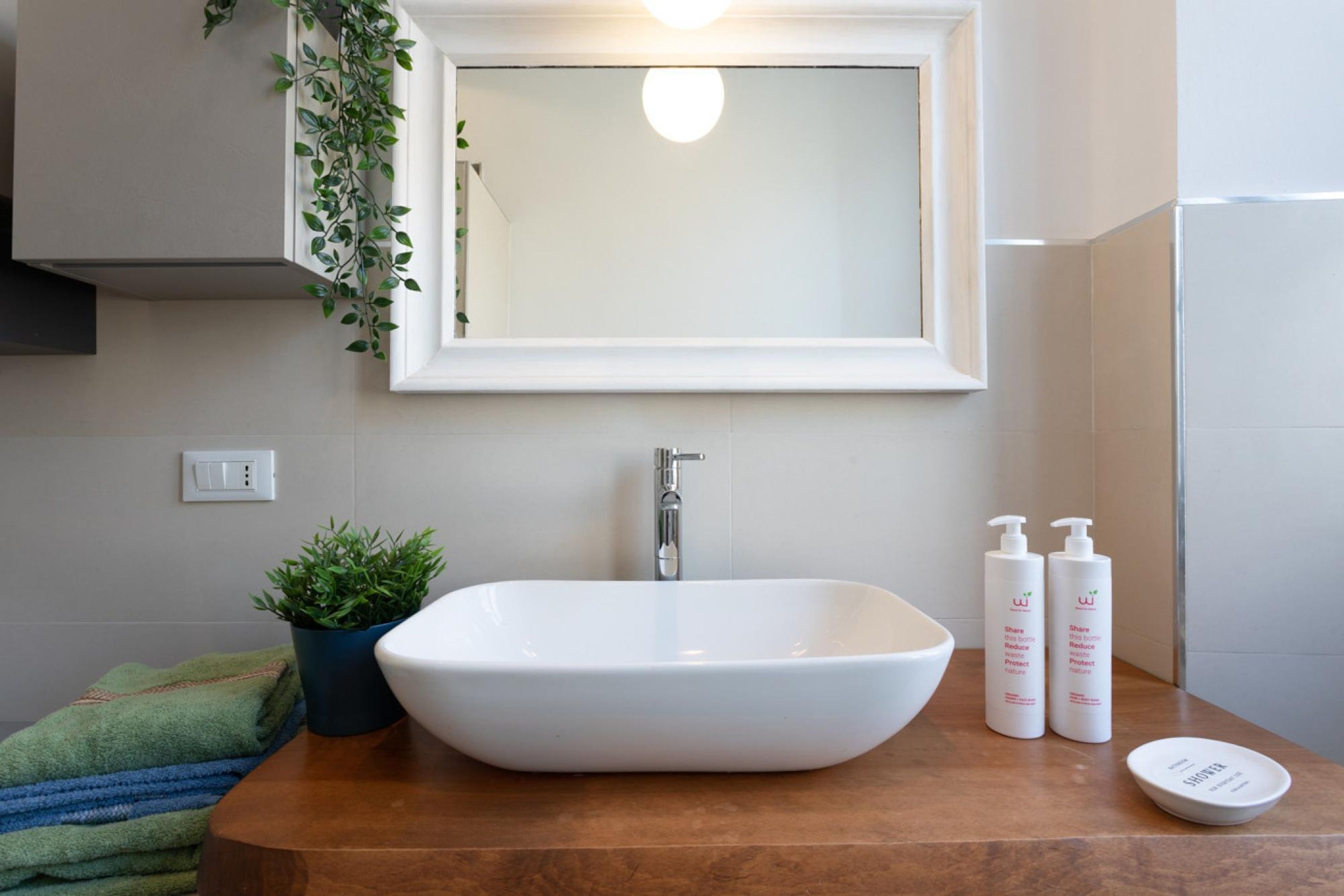 A bathroom with a white sink, a mirror, and two bottles of shampoo.