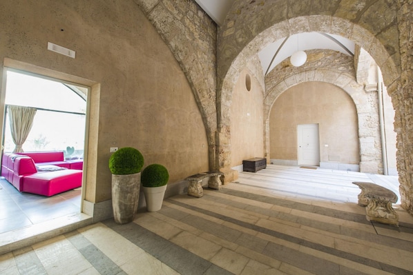 A spacious interior with stone arches, a modern seating area, and a large window.