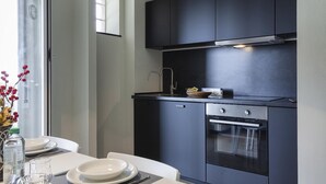 A modern kitchen with dark cabinetry, a built-in oven, and a dining area with a table set for two.
