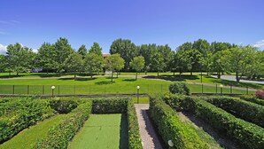 A well-maintained park with manicured lawns, hedges, and a variety of trees.