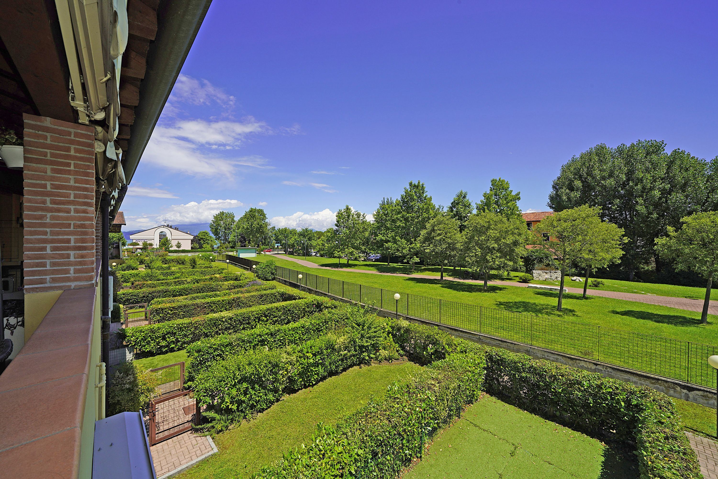 A landscaped garden with neatly trimmed hedges and a paved walkway.