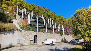 Een modern gebouw met een stenen gevel, een overdekt buitengebied en een geparkeerde bestelwagen.