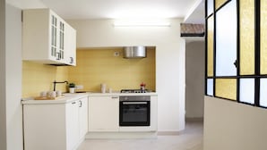 A compact kitchen with white cabinetry, a built-in oven, and a gas stove. - Liberty Apartment in Palazzo Diaz by Wonderful Italy (Naples)