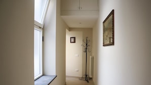 A narrow hallway with a window on the left, a coat rack on the right, and a radiator in the center. - Liberty Apartment in Palazzo Diaz by Wonderful Italy (Naples)
