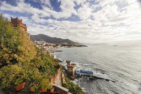 Uma vila costeira com um castelo histórico, um cais e vista para o mar.
