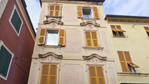 A multi-story building with yellow shutters and ornate architectural details. - Santa Chiara Apartment by Wonderful Italy (Genoa)