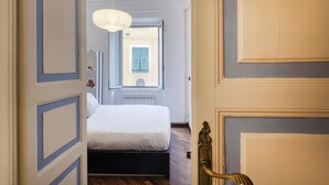 A bedroom with a bed, a window, and a door with a brass handle. - Santa Chiara Apartment by Wonderful Italy (Genoa)