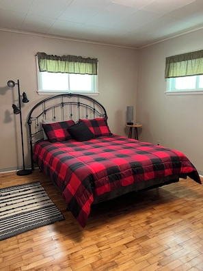 A bedroom with a bed, a floor lamp, a standing lamp, and a window with curtains.