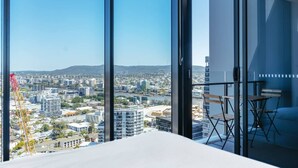 Ein modernes Hotelzimmer mit großen, raumhohen Fenstern und Blick auf die Stadt.